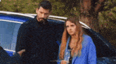 a man and a woman are standing next to a car .