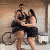 a man and a woman are dancing in front of a bicycle in a garage .