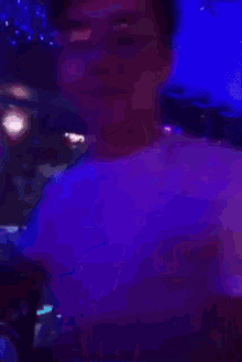 a man in a white shirt is standing in a dark room with blue lights behind him