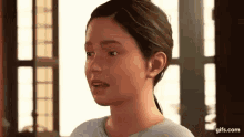 a young girl is standing in front of a window looking at the camera .