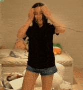 a woman wearing shorts and a black shirt is standing in front of a bed with stuffed animals on it