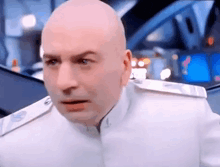 a bald man in a white uniform is making a funny face and looking at the camera .