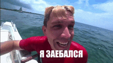 a man in a red shirt is sitting on a boat in the ocean with a caption in russian