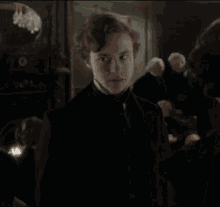 a man in a black coat is standing in a room with other men