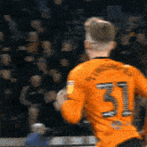 a soccer player in an orange jersey with the number 31 on the back