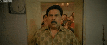 a man with a mustache is making a funny face in front of a clock that says xtoms 2005