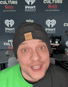 a man wearing a black beanie is standing in front of a iheart radio sign