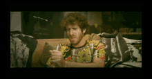 a man with a beard is sitting on a couch holding a can
