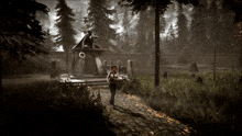 a woman walking down a path in the woods near a building