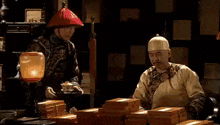a man wearing a hat and a gold robe is talking on a cell phone .