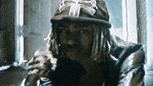 a man with dreadlocks is wearing a hat with the letter t on it