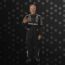 a man in a petronas racing suit waves his hand