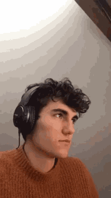 a young man wearing headphones and a sweater is making a funny face .