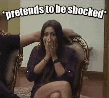 a woman is sitting in a chair and covering her mouth with her hands while a man holds her head .