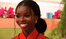 a woman wearing a red top and earrings smiles for the camera