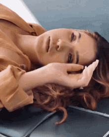 a woman laying on a couch with her hand on her face