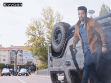 a man is standing next to a jeep that has a broken wheel