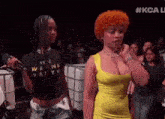 a woman in a yellow dress is standing next to another woman in a black t-shirt .