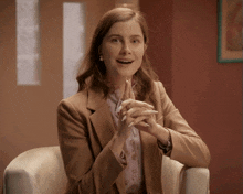 a woman in a brown jacket is clapping her hands