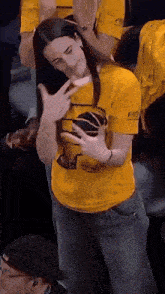 a woman wearing a yellow shirt that says bad on the sleeve