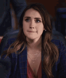 a woman in a plaid jacket is sitting with her hands folded