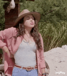 a woman wearing a cowboy hat and a pink shirt .