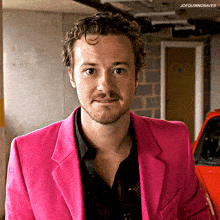 a man in a pink jacket is standing in a garage