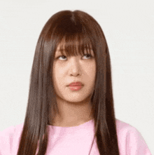 a woman with long hair and bangs is wearing a pink shirt .