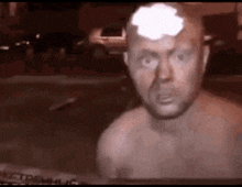a man without a shirt is standing in front of a car with a smoke coming out of his head .