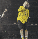 a woman singing into a microphone wearing a yellow shirt that says lulu dan on it