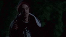 a man wearing a beanie and a red shirt is smiling in the dark .
