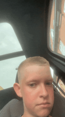 a young man with a shaved head is sitting in a car