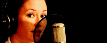 a woman is smiling in front of a microphone and wearing headphones