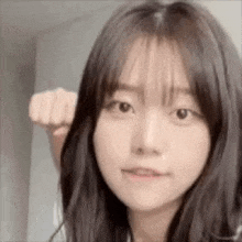 a close up of a young woman with long hair making a fist .