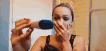 a woman covering her mouth with her hand while holding a thermometer