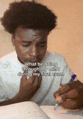 a young man sitting at a desk with a book and a pen in his hand while a tiktok video is being viewed