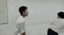 two men are fighting each other in front of a wall .