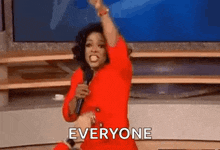 a woman in a red dress is holding a microphone and screaming at the camera .