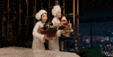 two women in bathrobes carrying baskets of food and drinks