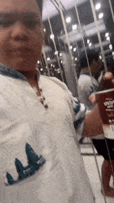 a man is taking a selfie in front of a mirror while holding a can of soda .