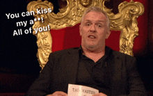 a man sitting in a chair holding a piece of paper that says " you can kiss my a "