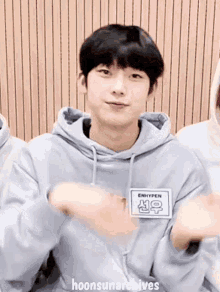 a young man wearing a gray hoodie is clapping his hands .