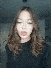a woman with red lips and freckles is wearing a black sweater