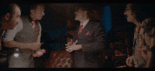 two men are standing next to each other in a dark room and one has a tattoo on his face .