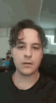 a close up of a man 's face with a black shirt on making a funny face .