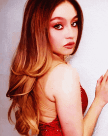 a woman in a red dress is looking over her shoulder at the camera