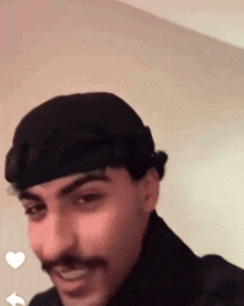 a man with a mustache wearing a black hat and smiling