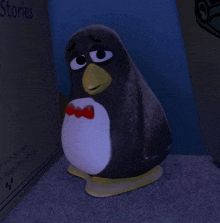 a stuffed penguin with a bow tie is standing in front of a book called stories