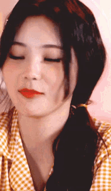 a close up of a woman 's face with her eyes closed and a plaid shirt on