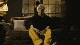 a man in yellow pants sits on a brown leather couch